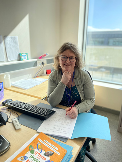 Photo of Bev Brookes sat at her desk in her office in school